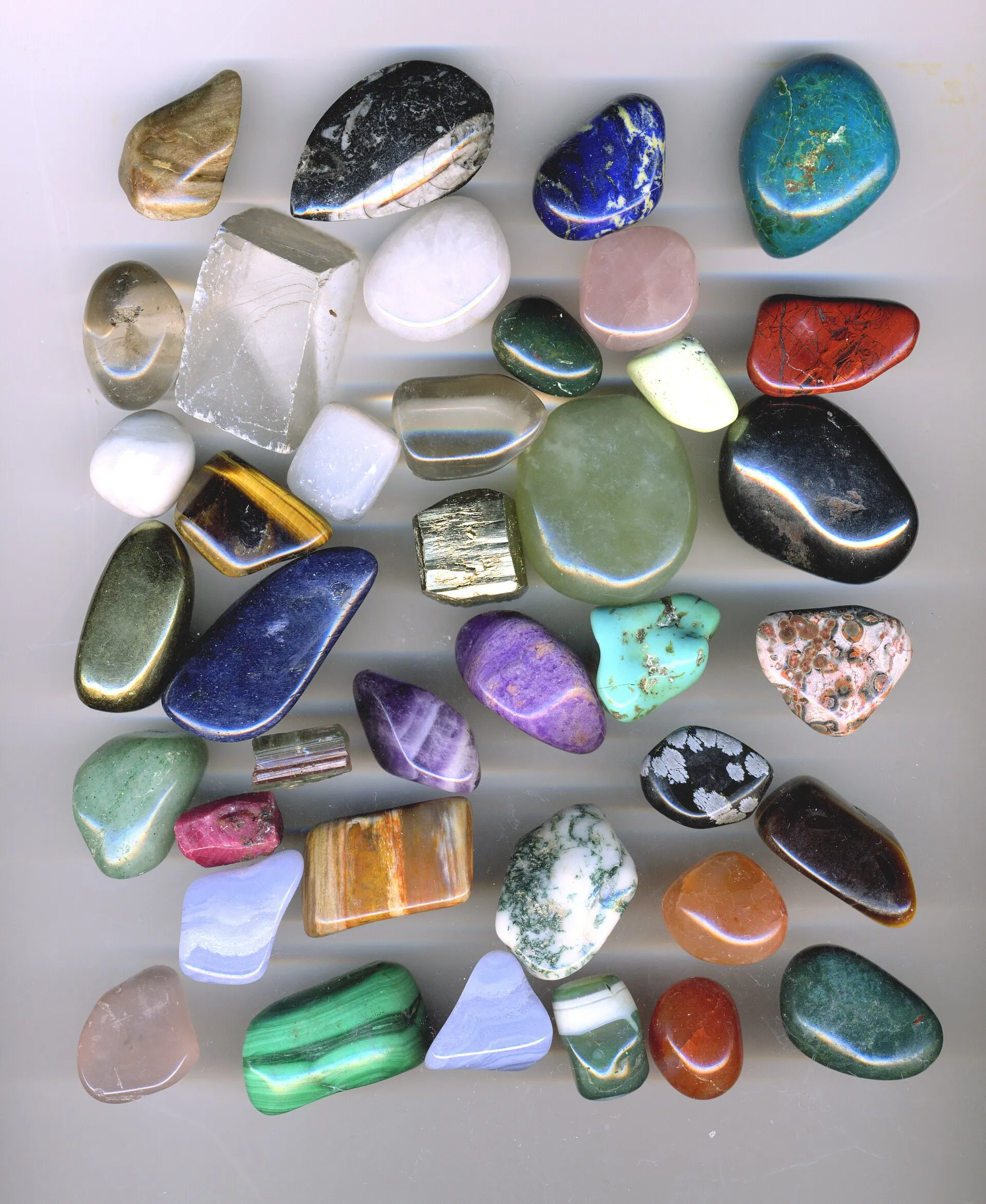 An assortment of colorful tumbled gemstones on a white background